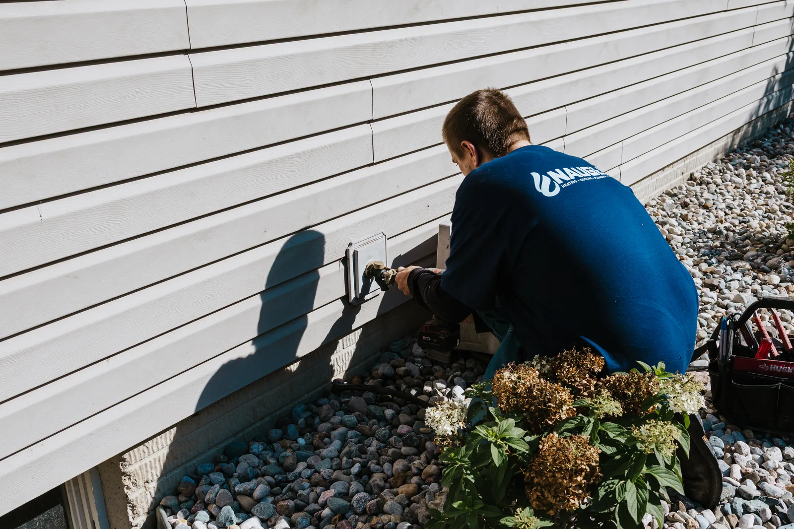 Naugle cooling technician servicing a residential AC condenser